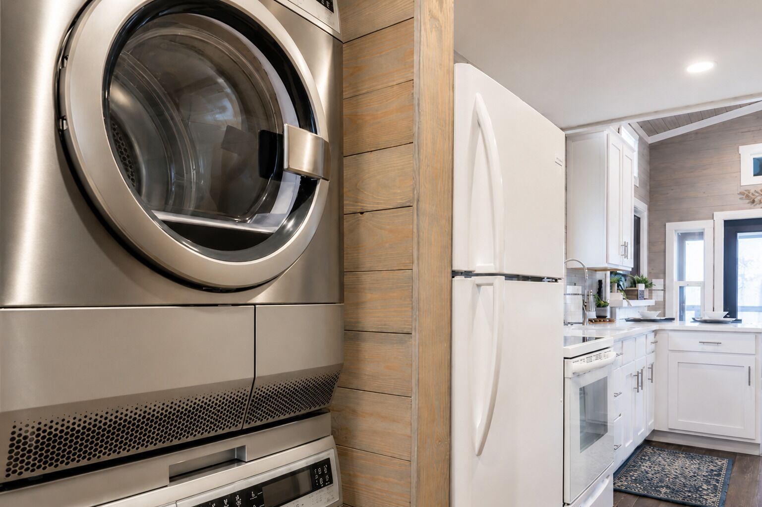 A modern kitchen with a built-in stainless steel washer, a white refrigerator, and wooden cabinetry.