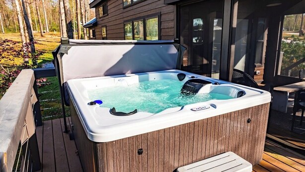 A hot tub on a wooden deck with a house in the background. - Edgewater at The Retreat at Water's Edge (Tracy City)