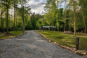 Un chemin de gravier mène à un chalet entouré d’arbres.