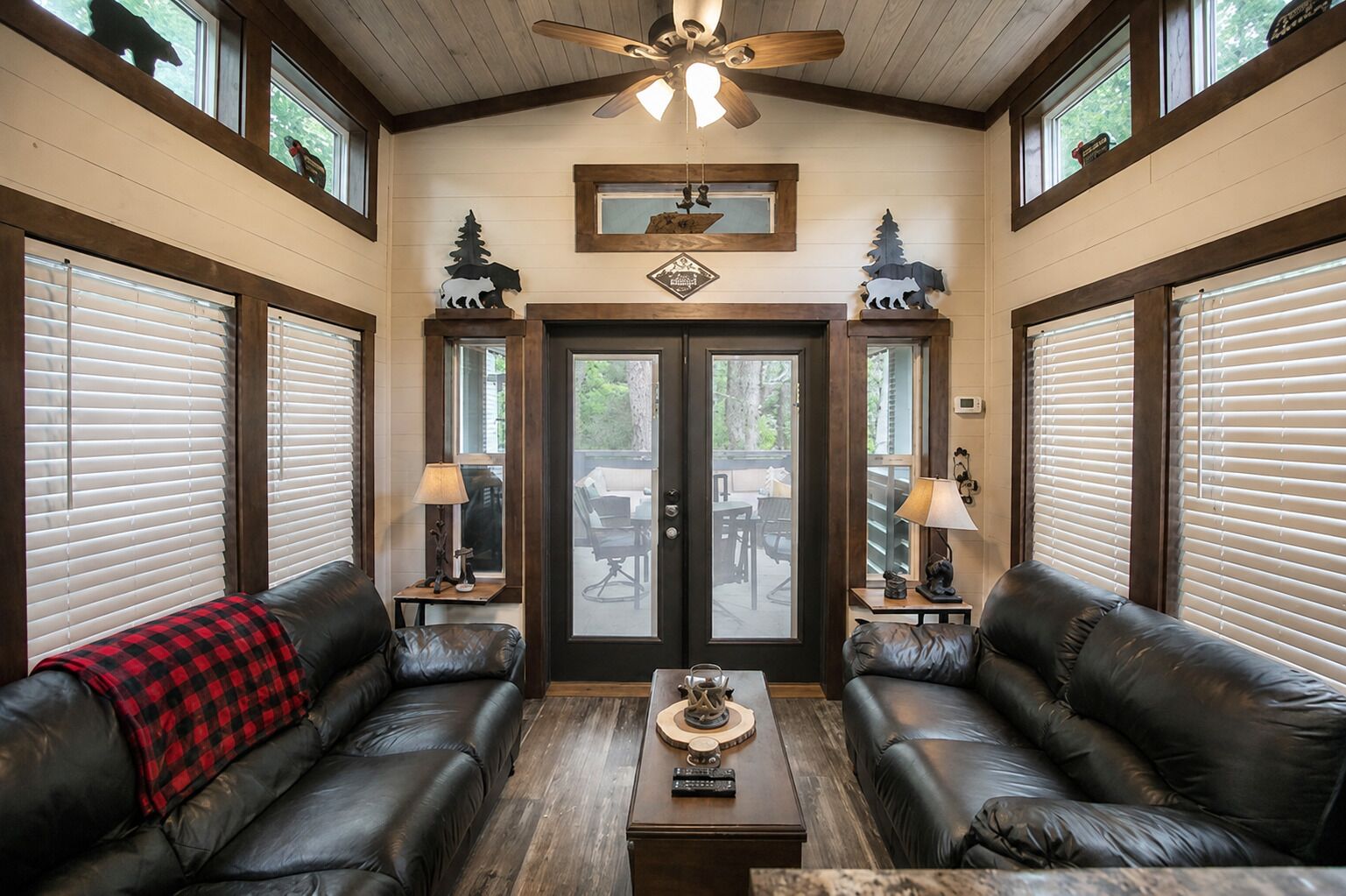 A room with two leather sofas, a wooden coffee table, and a ceiling fan.