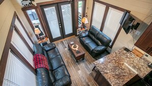 A spacious living area with a black leather sofa, a coffee table, and a kitchen counter. - Jenny's Retreat at The Retreat at Deer Lick Falls (Monteagle)