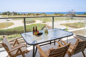 Enjoy a serene meal on the balcony with a clear view of the landscaped area and distant trees.