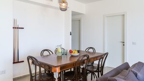 Een eetruimte met een houten tafel, stoelen, een schaal fruit en een waterkan.