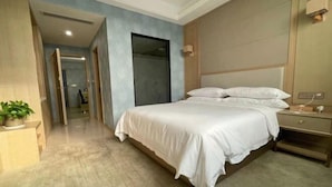 A bedroom with a large bed, a bedside table, a nightstand, and a potted plant. - Vienna International Hotel (Wenzhou Rui'an Tangxia) (Rui'an)