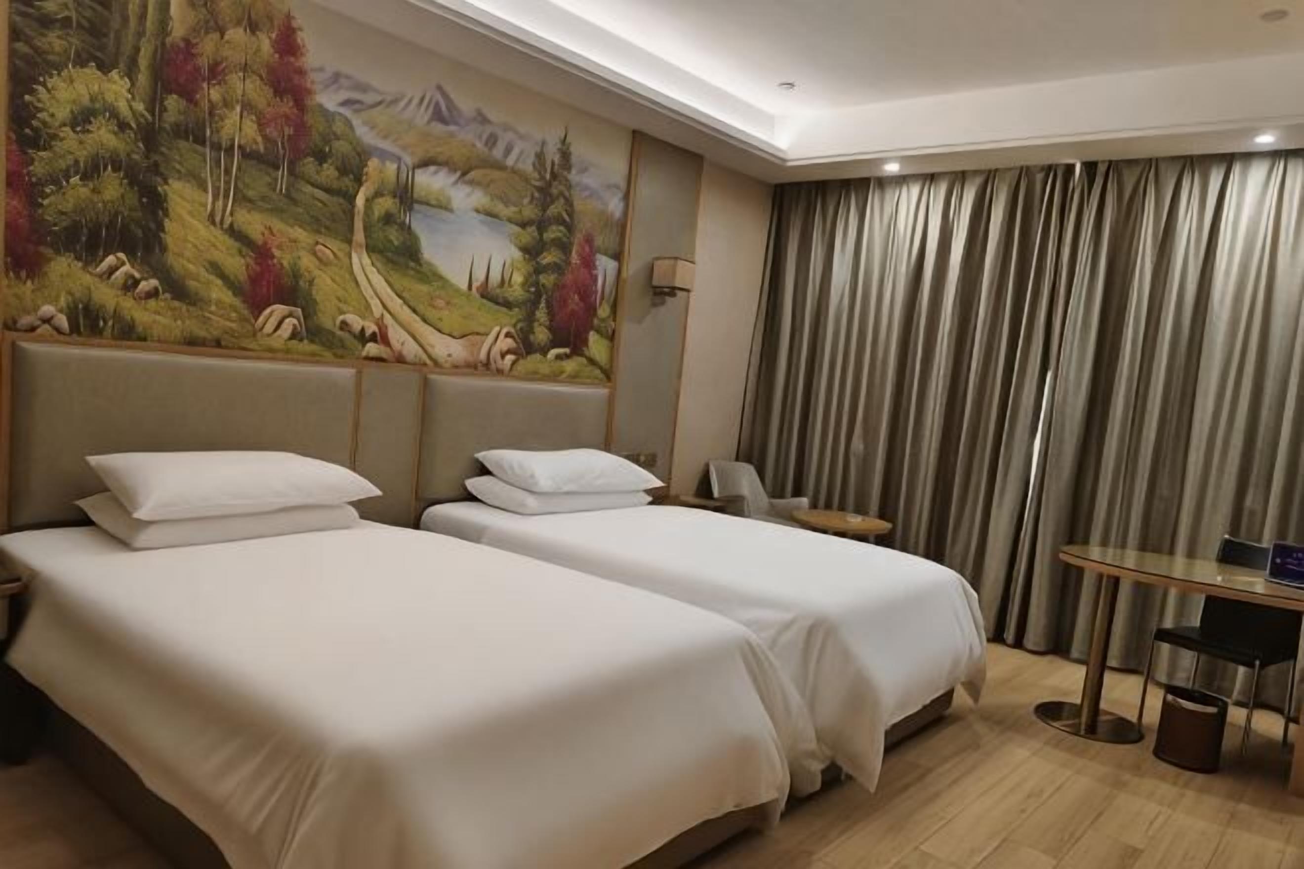 A hotel room with two beds, a desk, a chair, a painting, and a view of a mountain landscape.