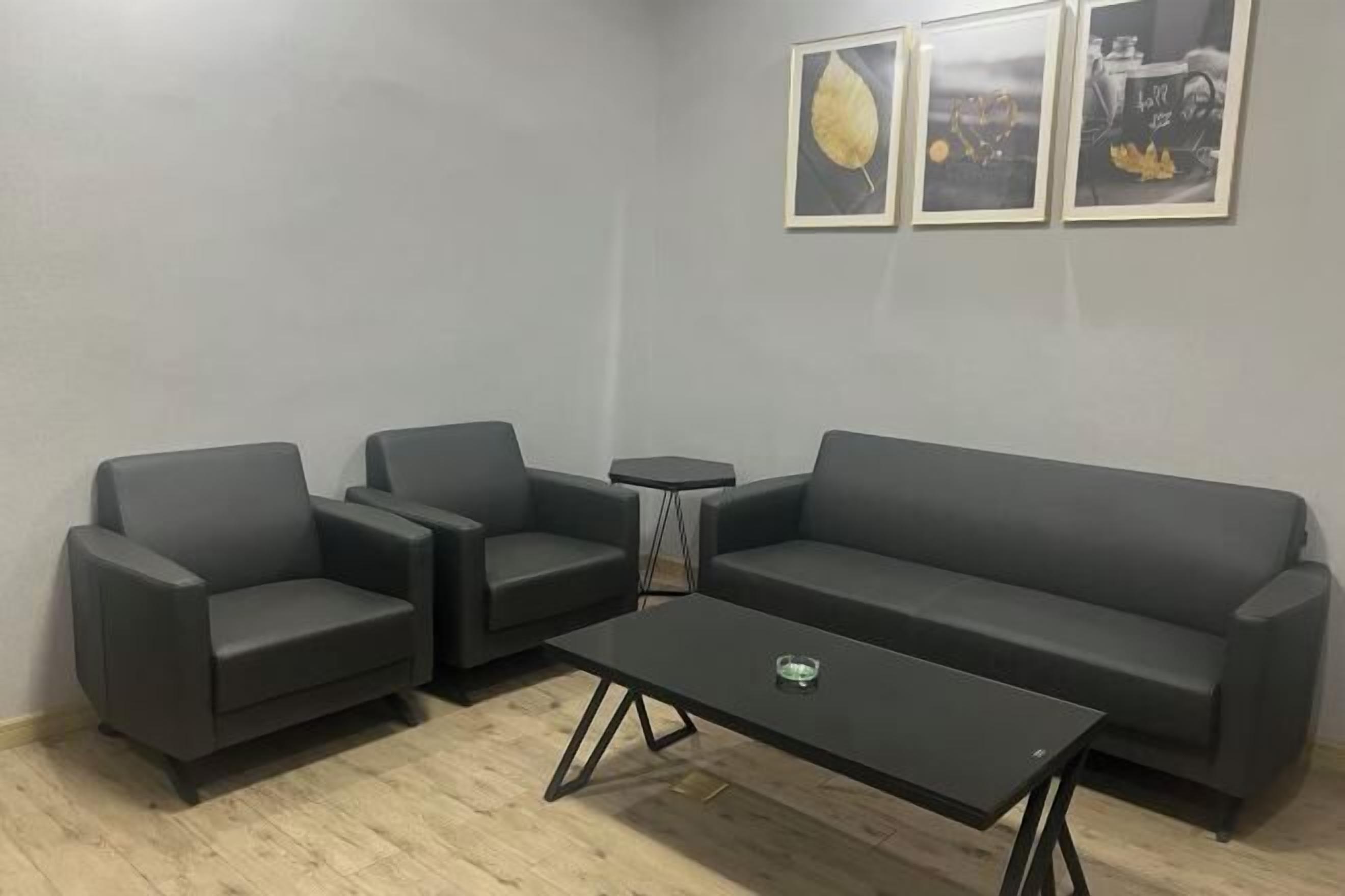 A modern living room with a grey sofa, two armchairs, and a coffee table.