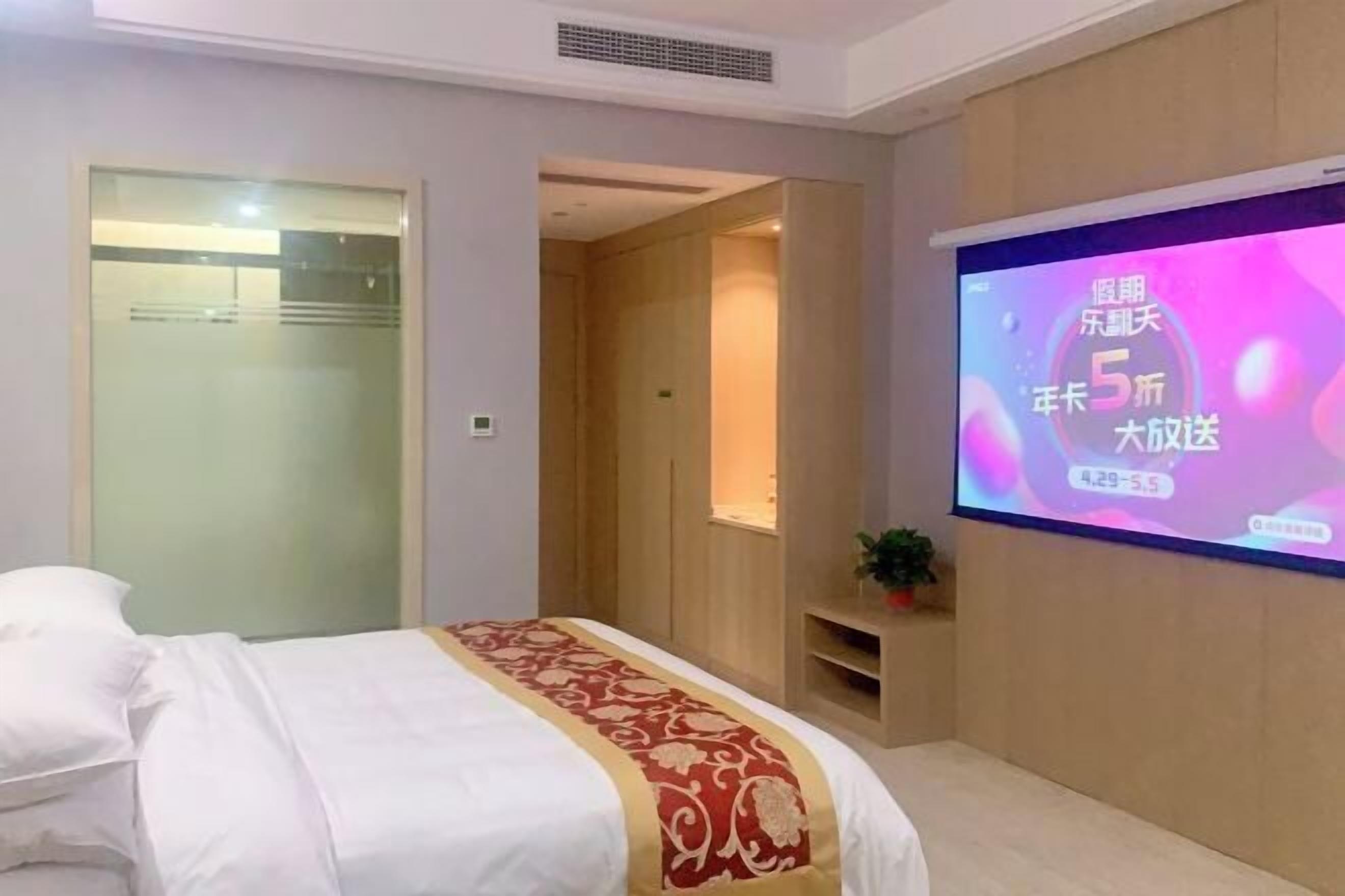 Una habitación de hotel con una cama, una pantalla de televisión mostrando un mensaje y una puerta de madera.