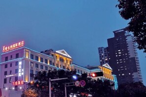 A hotel with a modern facade, illuminated signage, and a traffic light in the foreground. - Vienna International Hotel (Wenzhou Rui'an Tangxia) (Rui'an)