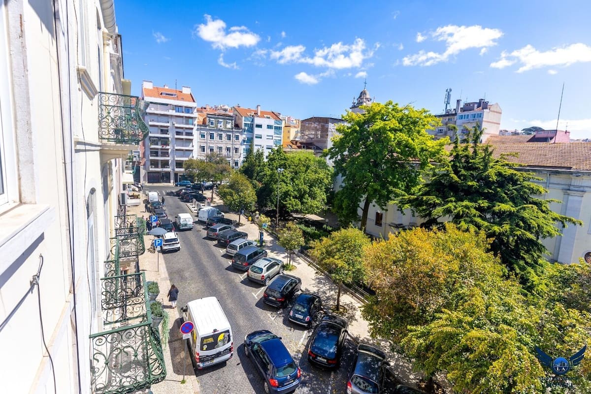A street view with parked cars, buildings, and trees.