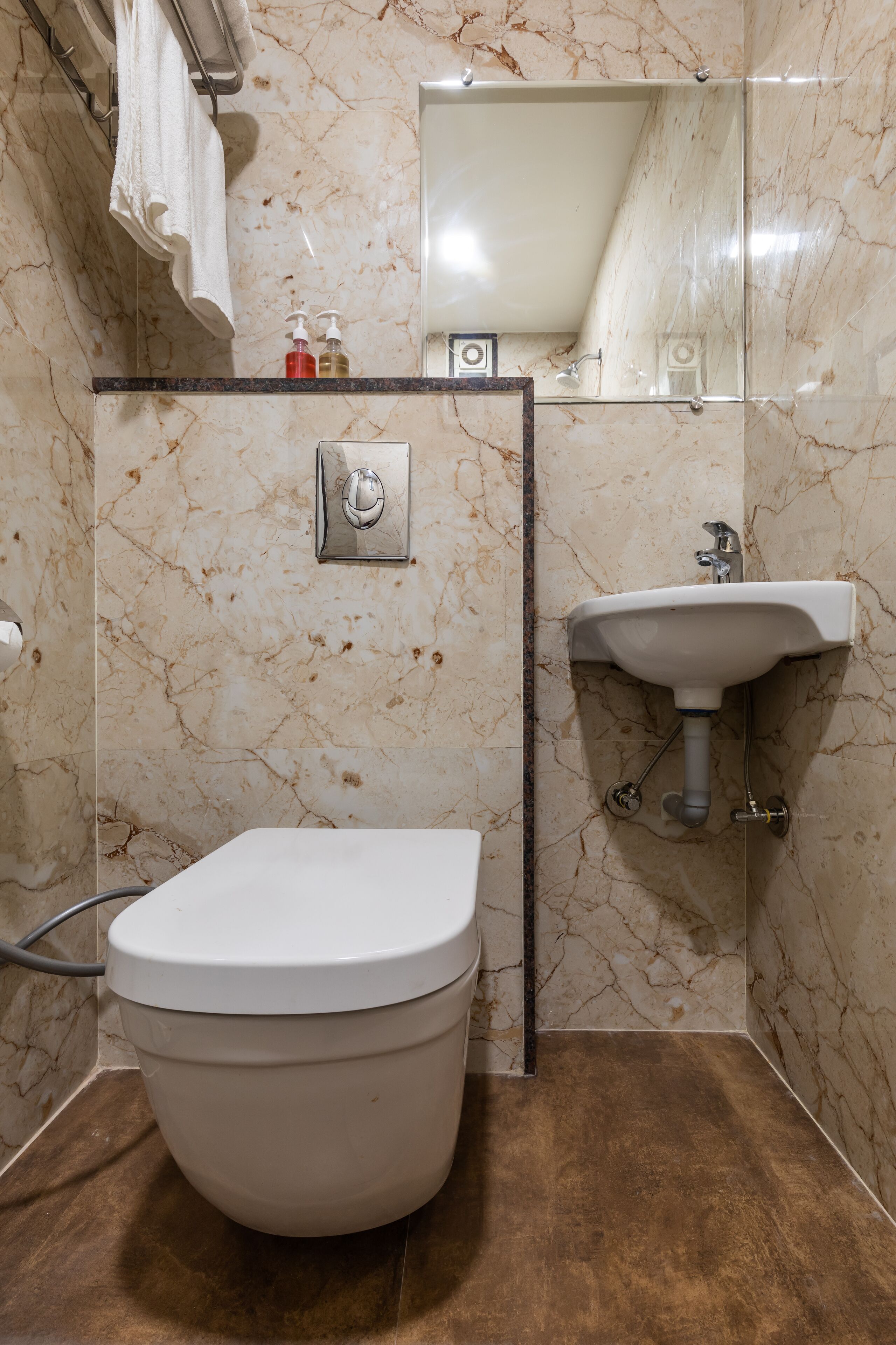 A bathroom with a toilet, sink, and marble walls.