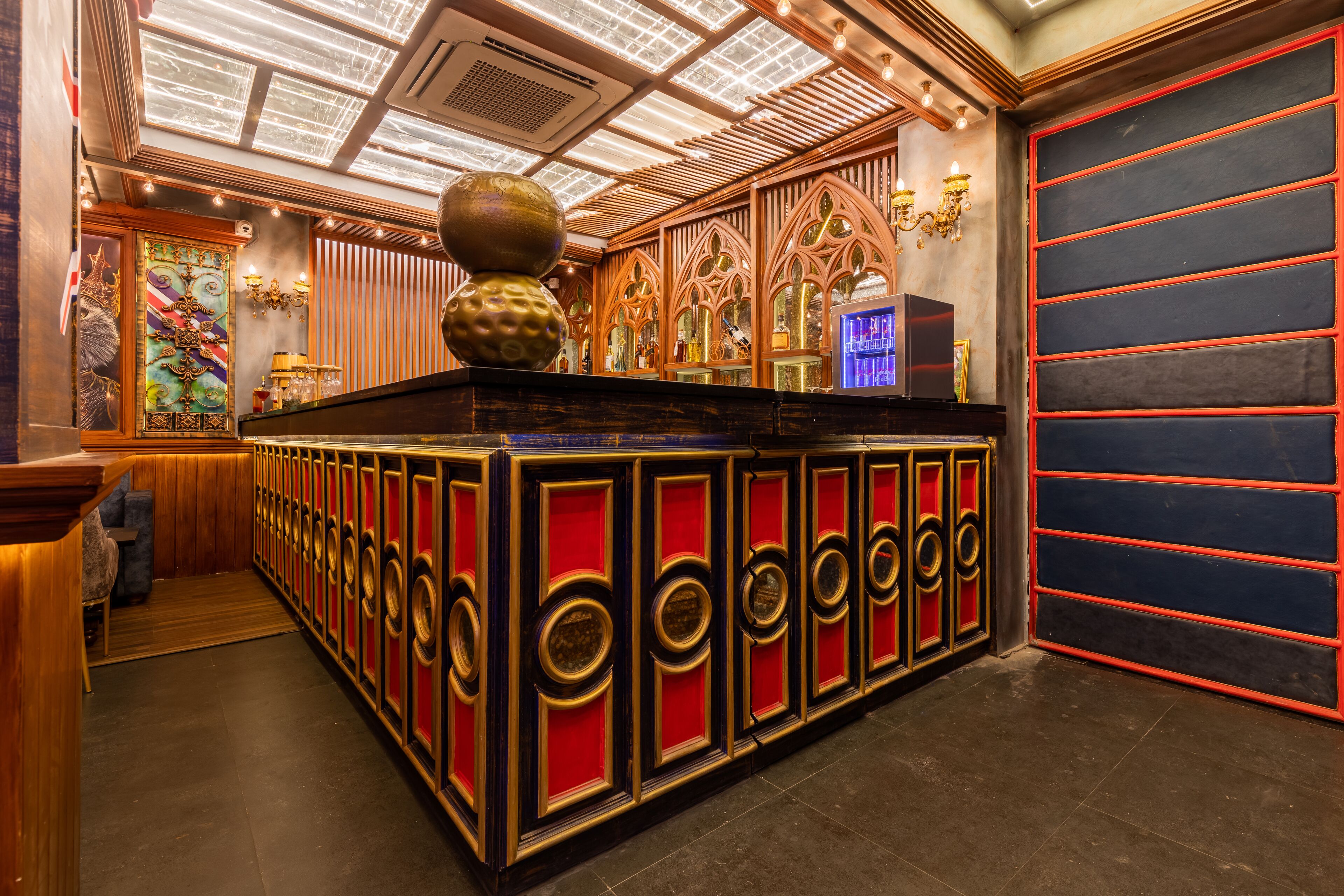 Una zona de bar con mostrador de madera, paneles decorativos en la pared y un techo con tragaluces.