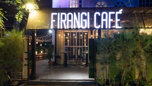 L’extérieur du Firangi Café présente une entrée bien éclairée, un espace extérieur aménagé avec des sièges et un chemin clairement visible menant à l’entrée.
