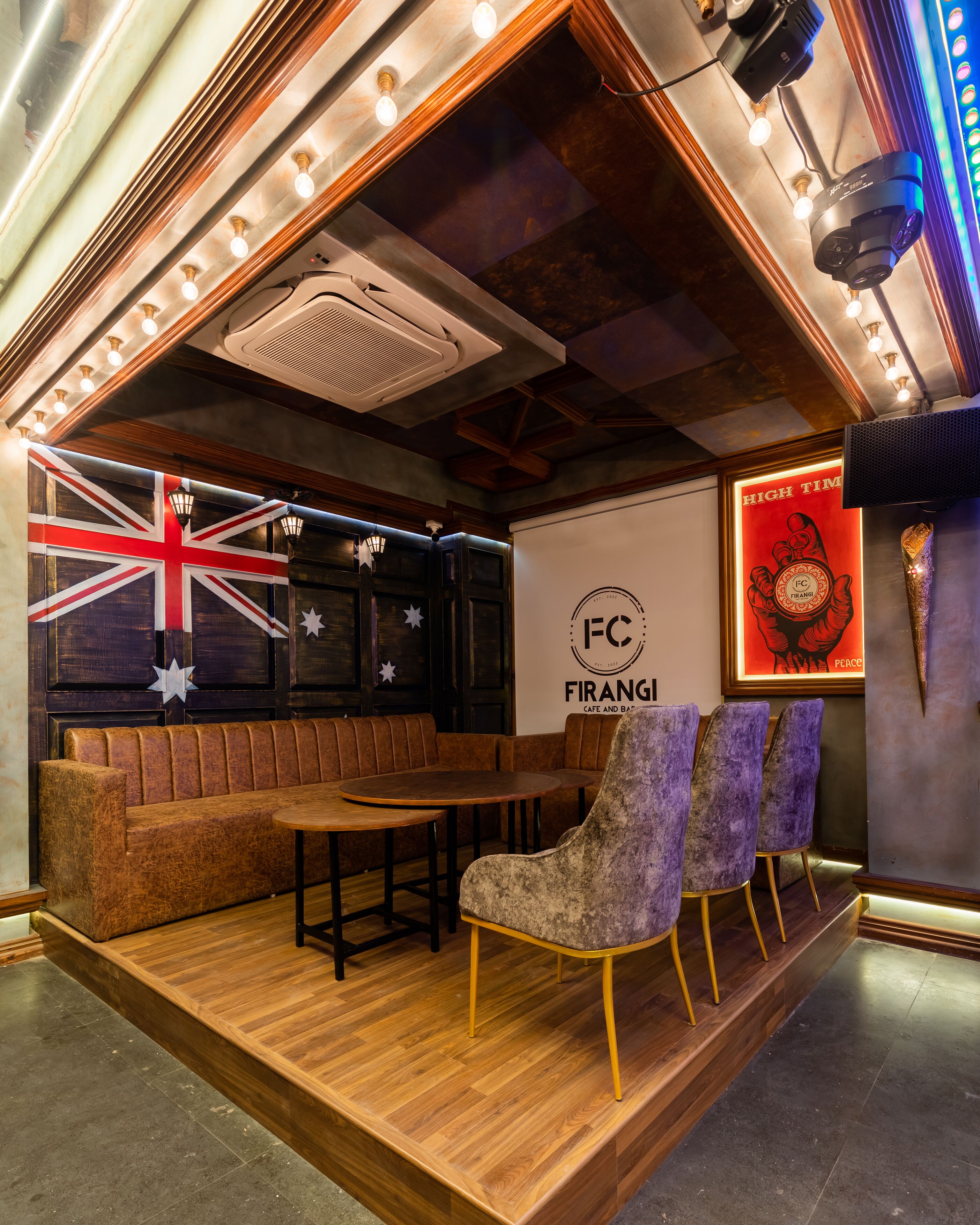 Angolo accogliente con una panca in legno e un tavolo, una parete con il cartello FC FIRANGI e una parete decorata con la bandiera britannica e stelle.