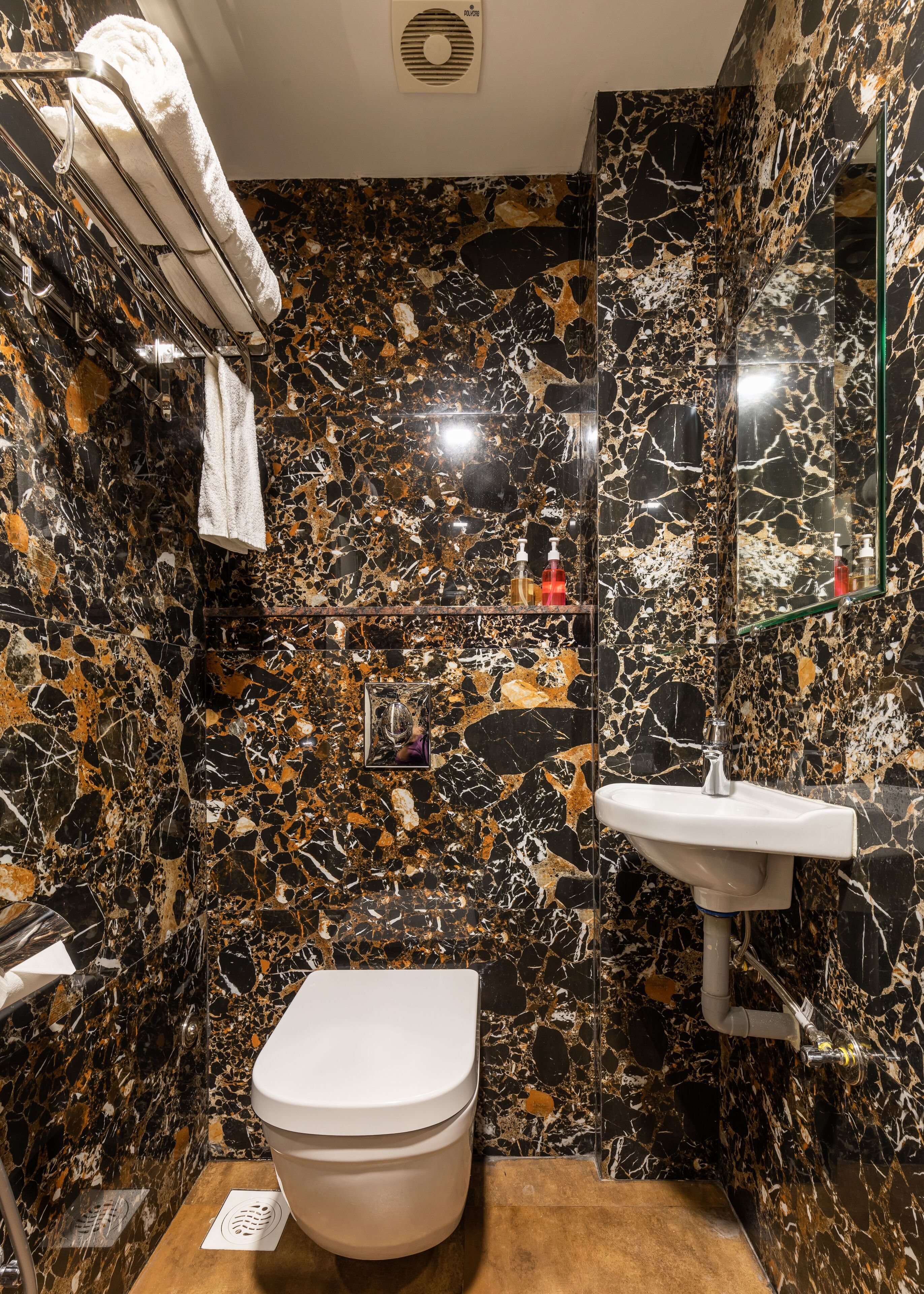 Un baño con lavamanos, inodoro y toallero de mármol.