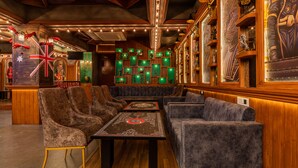 Un restaurant aux murs en bois, aux vitrines illuminées de couleur verte et aux fauteuils confortables.