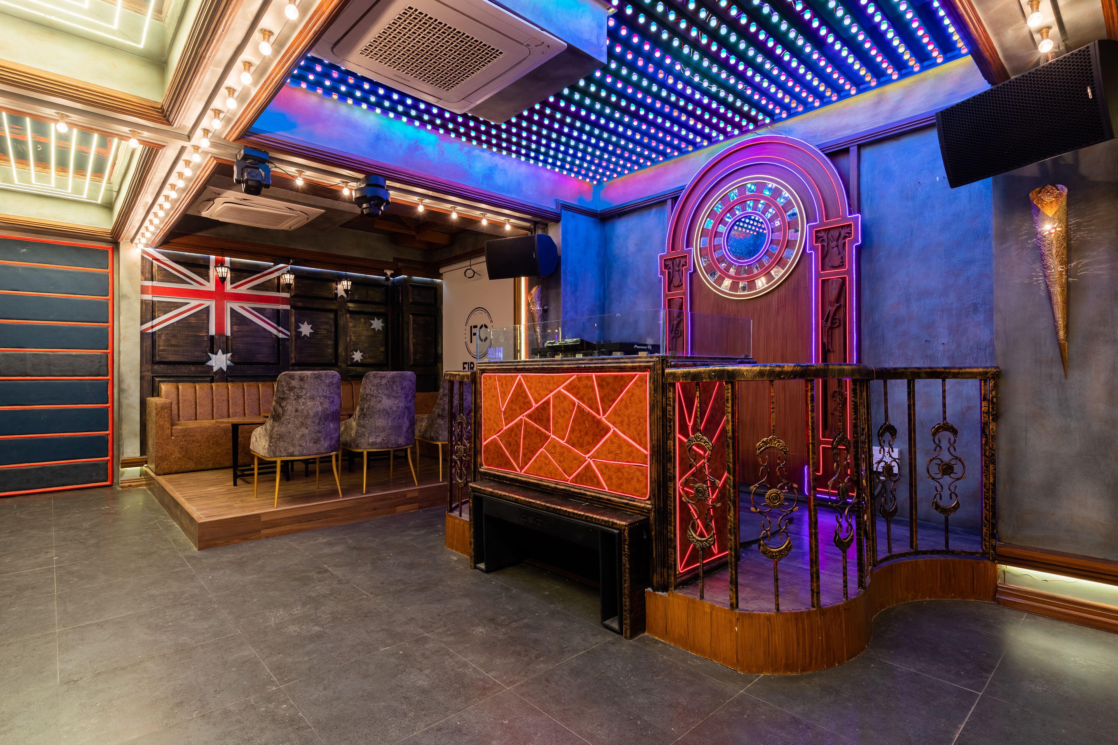 Una habitación con escenario, asientos y una pared decorativa con la bandera Union Jack.
