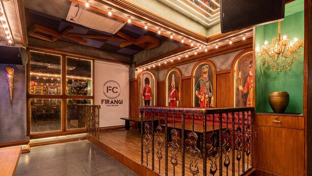 Un espace d’accueil avec un comptoir en bois, un lustre et un mur orné de portraits encadrés.