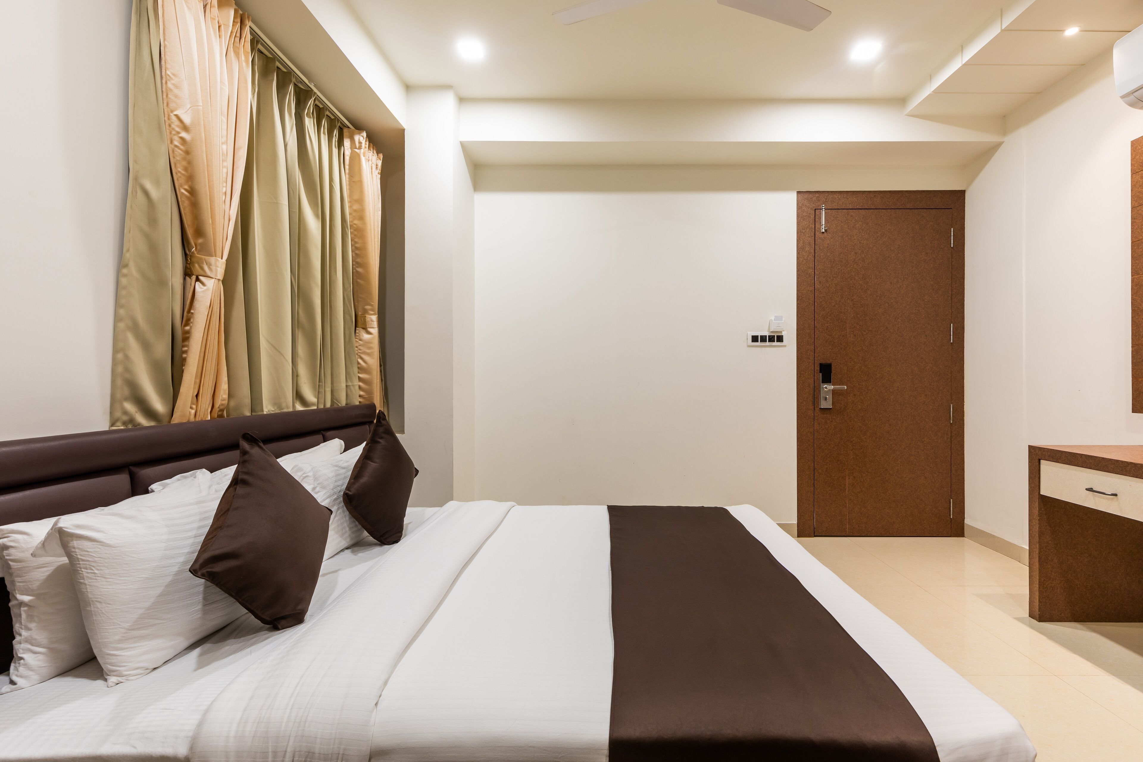 A hotel room with a bed, a nightstand, a dresser, and a door.