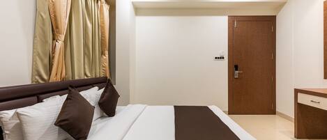 A hotel room with a bed, a nightstand, a dresser, and a door.