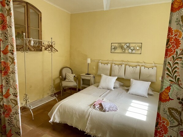 Ein Schlafzimmer mit Bett, Stuhl, Nachttisch und Spiegel.