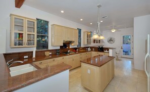 A modern kitchen with granite countertops, wooden cabinets, and a large island.