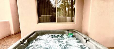 A hot tub in a covered outdoor area with a window above it.