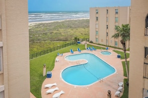 Relax by the rooftop pool surrounded by lounge chairs and sun loungers, with a view of the ocean.