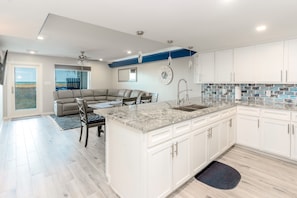 Enjoy meals in the spacious kitchen and dining area, featuring a large island and a comfortable seating area with a view of the outdoors.