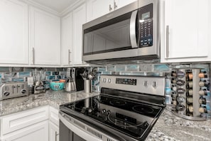 Enjoy cooking in this well-equipped kitchen with stainless steel appliances, a granite countertop, and a spice rack.