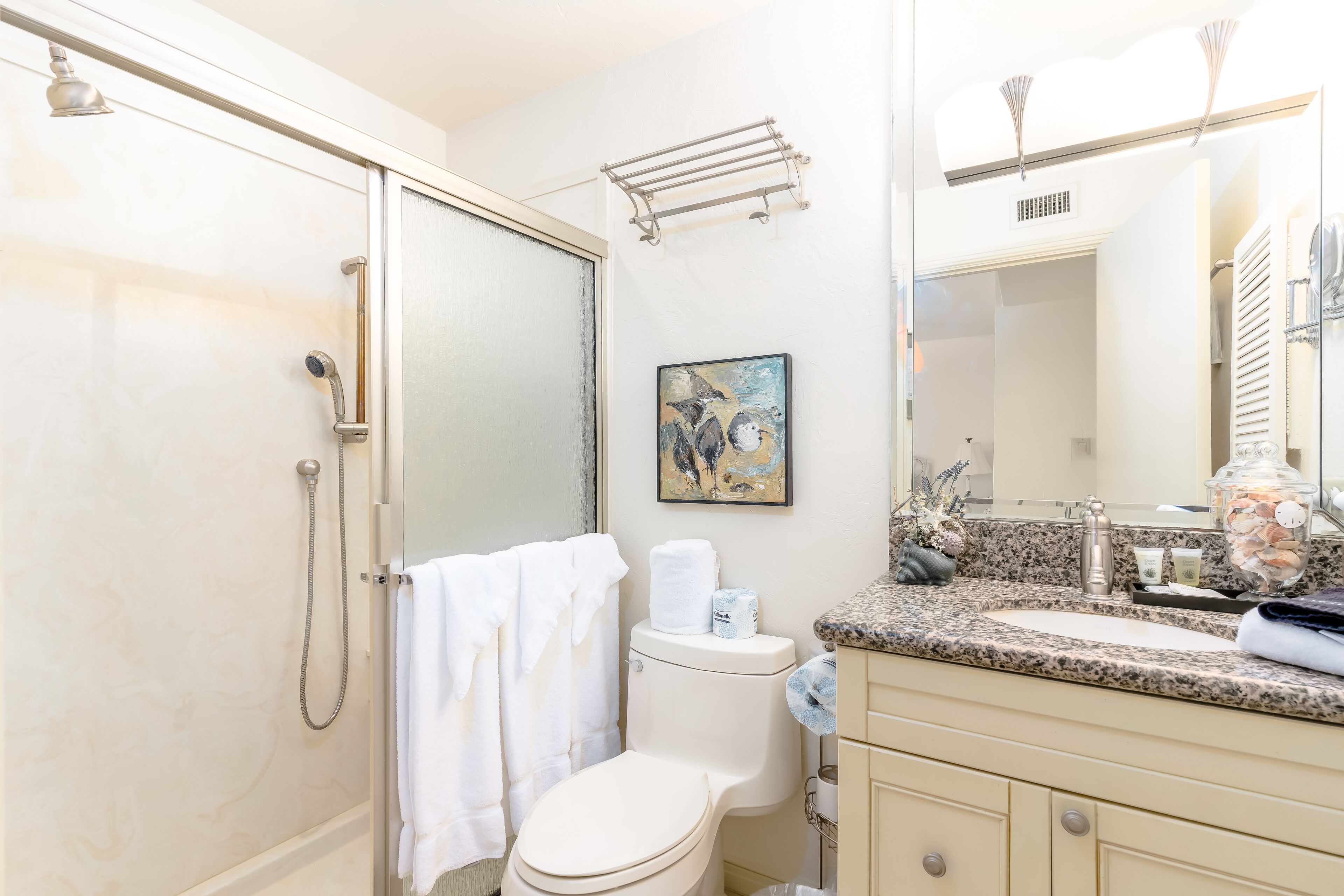 A bathroom with a shower, toilet, sink, and a towel rack.