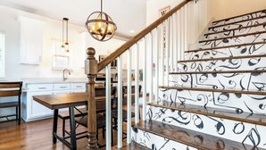 A staircase with a unique black and white pattern, a wooden handrail, and a chandelier.