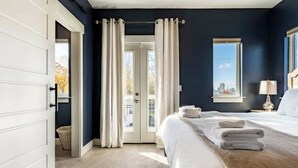 A bedroom with a bed, a window, a door, and a view of the outdoors.