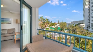 Enjoy the city view from this balcony with a wicker table and sofa.