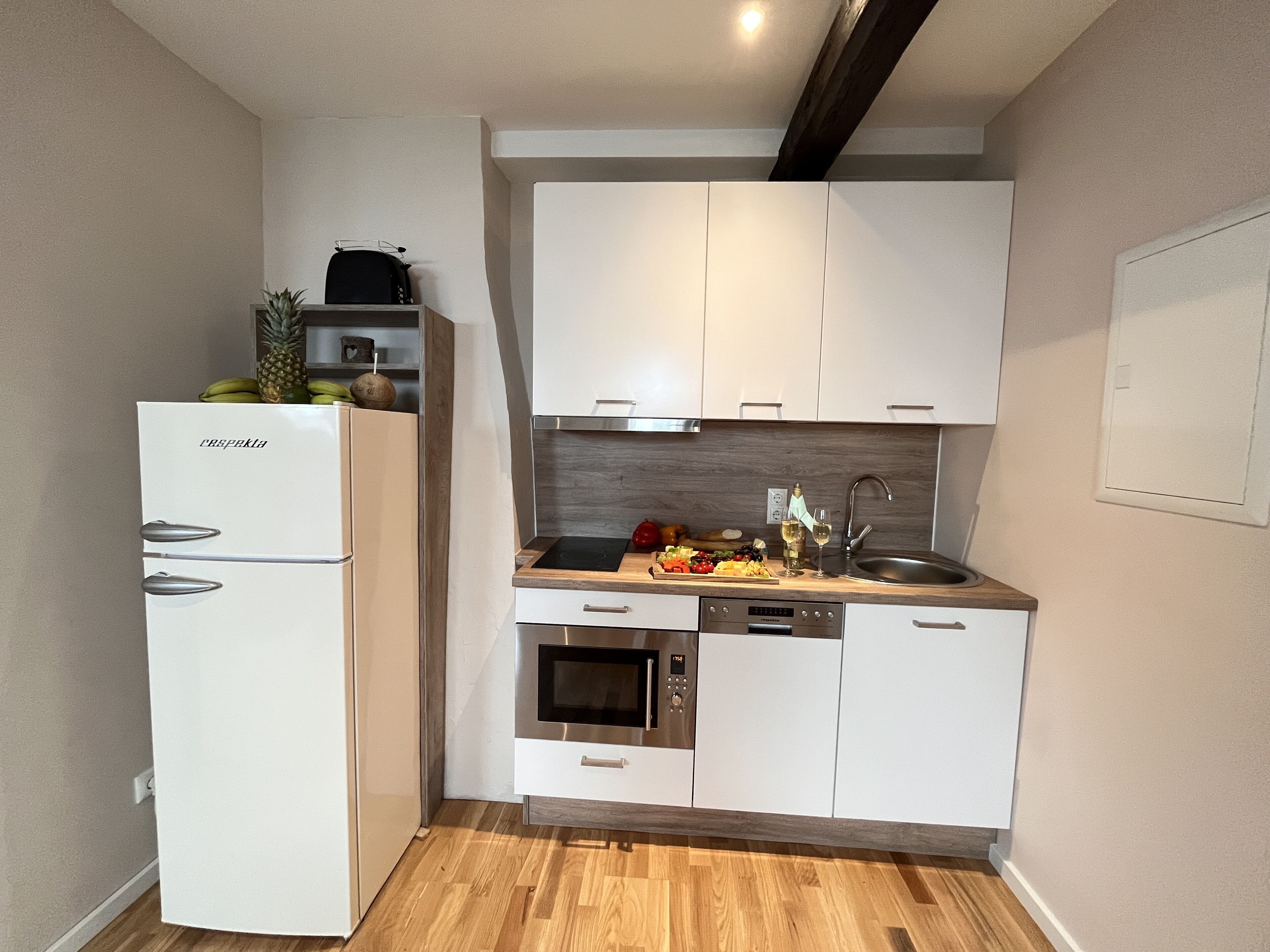 A compact kitchen with white cabinets, a built-in oven, and a dishwasher.