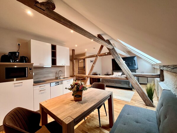 A modern loft-style apartment with a kitchen, dining area, and sleeping space.