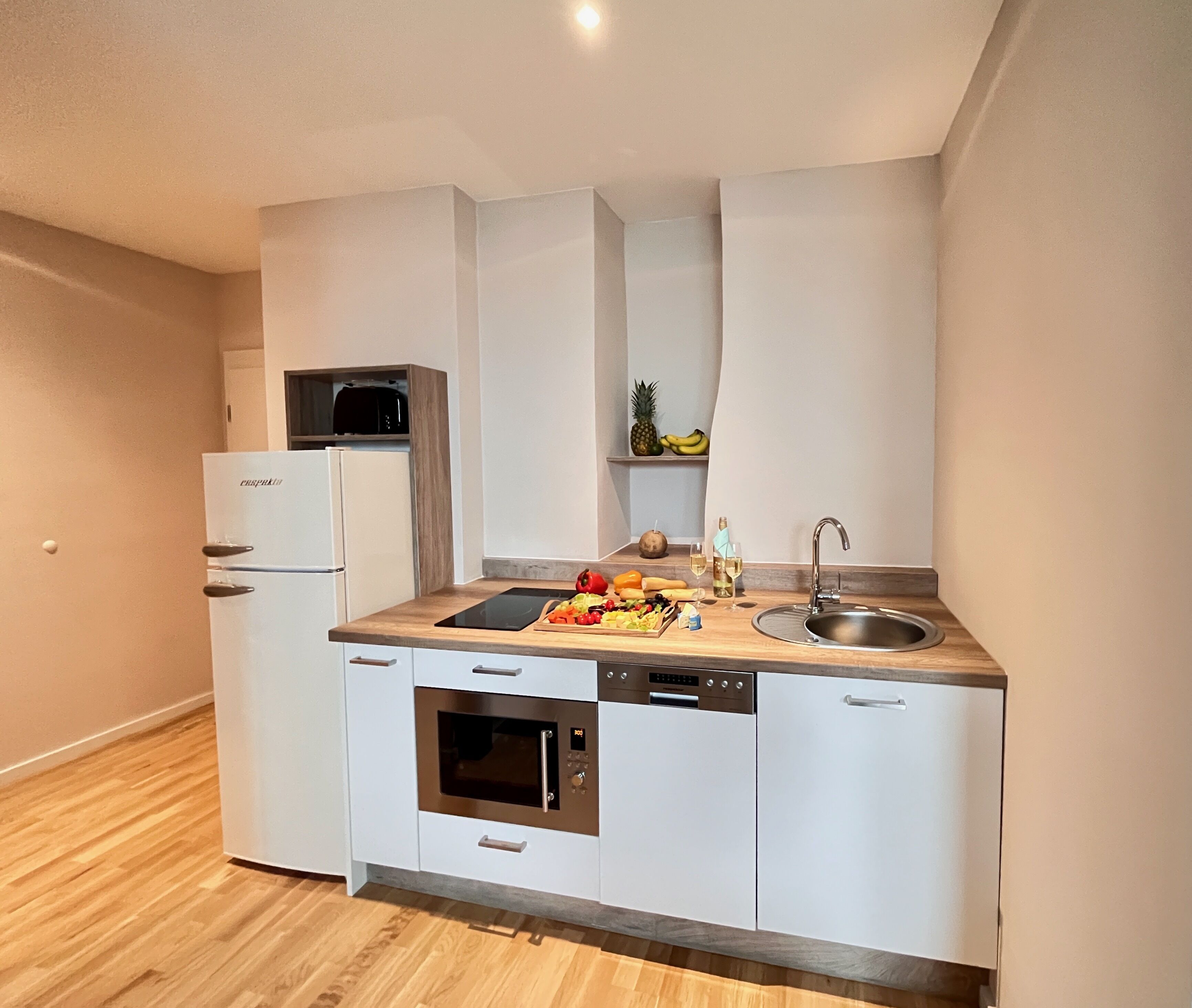 Cocina compacta equipada con refrigerador, horno, microondas y pileta.