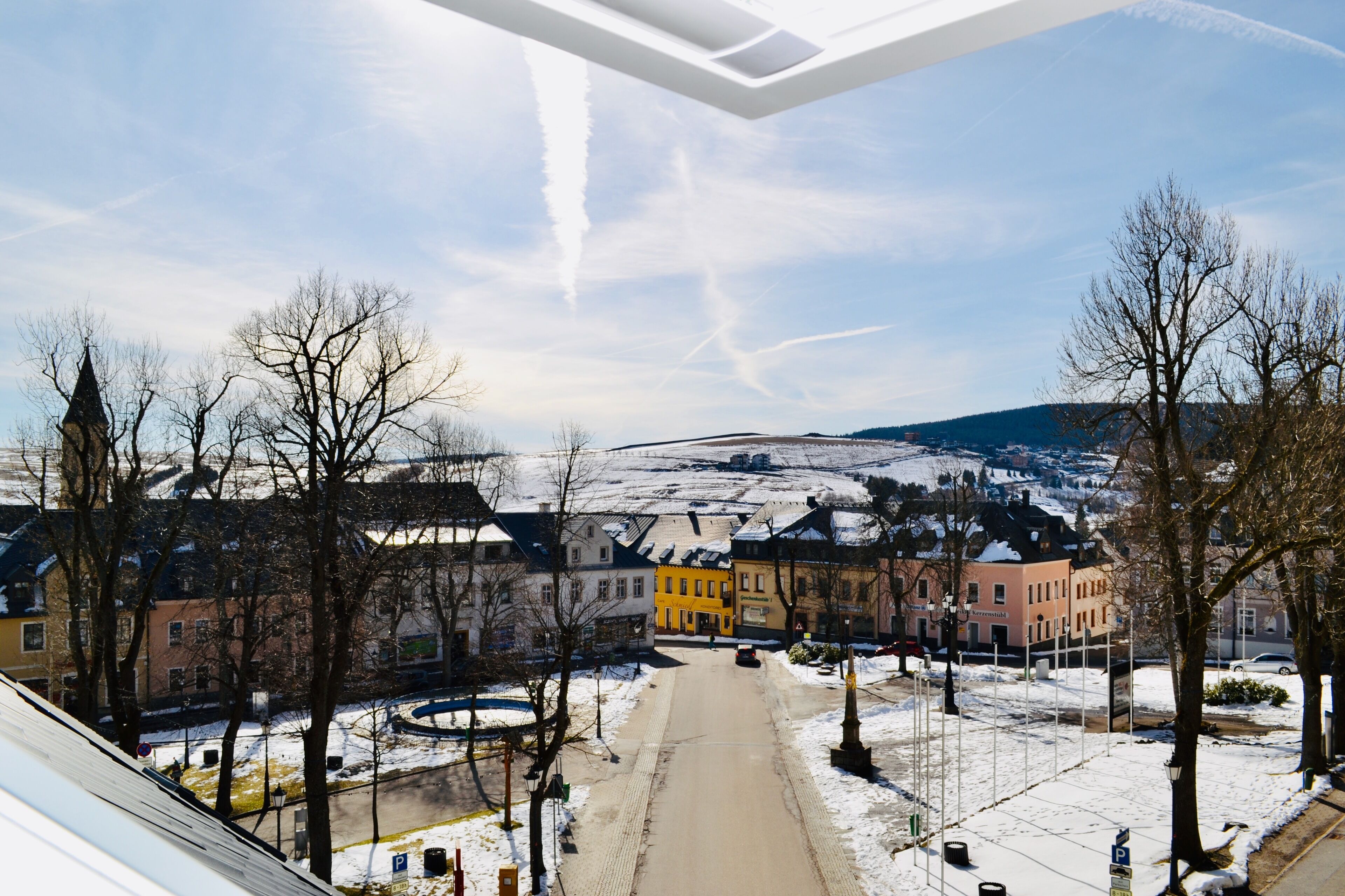 A snow-covered street with buildings and a clear sky.