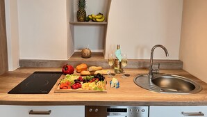 Una encimera de cocina con una tabla de cortar de madera, una botella de champán y un lavamanos.