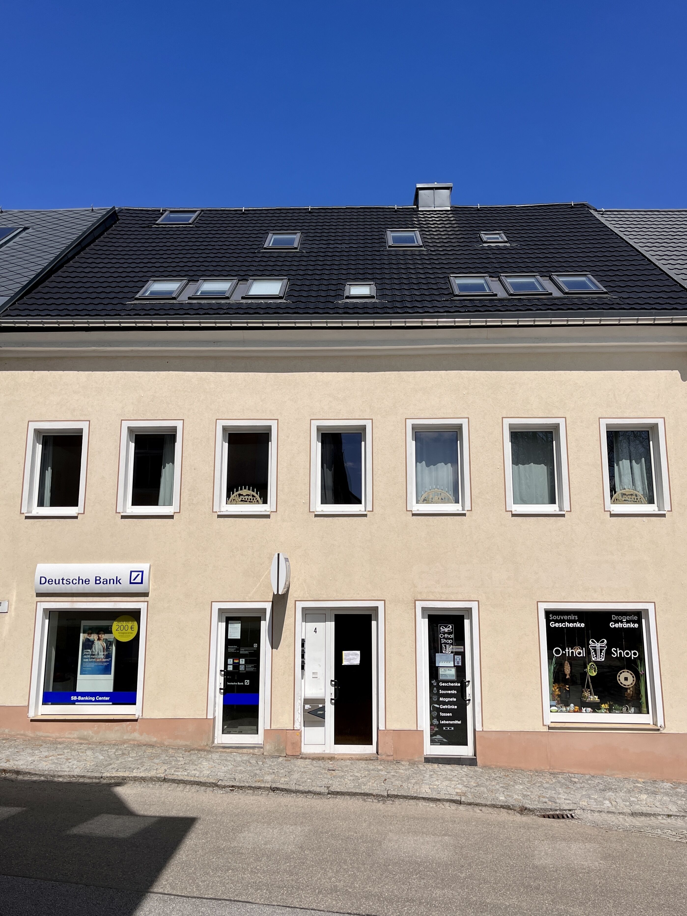 Een gebouw met een Deutsche Bank filiaal, een souvenirwinkel en een deur met het nummer 4.