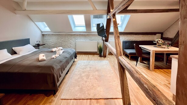 Un dormitorio tipo loft moderno con techo inclinado, tragaluces, cama, escritorio y silla.