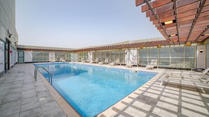 Une piscine intérieure à l’eau d’un bleu cristallin, entourée de chaises longues et dotée d’un sol carrelé.