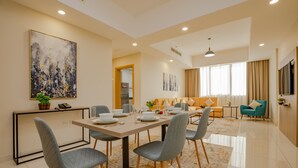 Un espace de salle à manger moderne, avec une longue table, des chaises à revêtement gris et une palette de couleurs neutres.