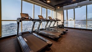 Une salle de sport équipée de tapis de course et offrant une vue sur la ville.