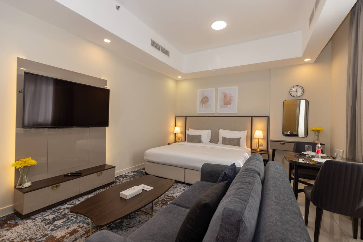 Une chambre d’hôtel moderne dotée d’un grand lit, d’un téléviseur à écran plat, d’un canapé, d’une table basse et d’un bureau avec une chaise.
