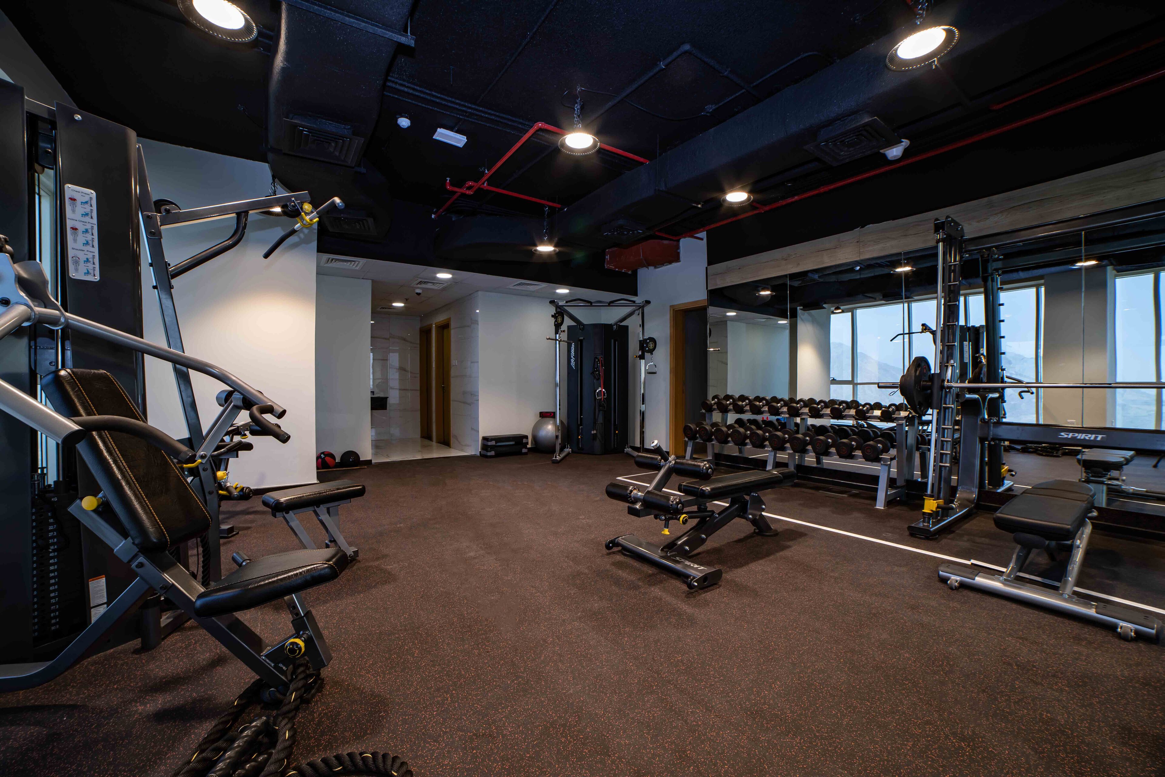 A gym with various exercise equipment, including treadmills, weight machines, and dumbbells.