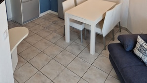 Kompakti keittiö, jossa on ruokailutila, sohva ja kattovalaisin.