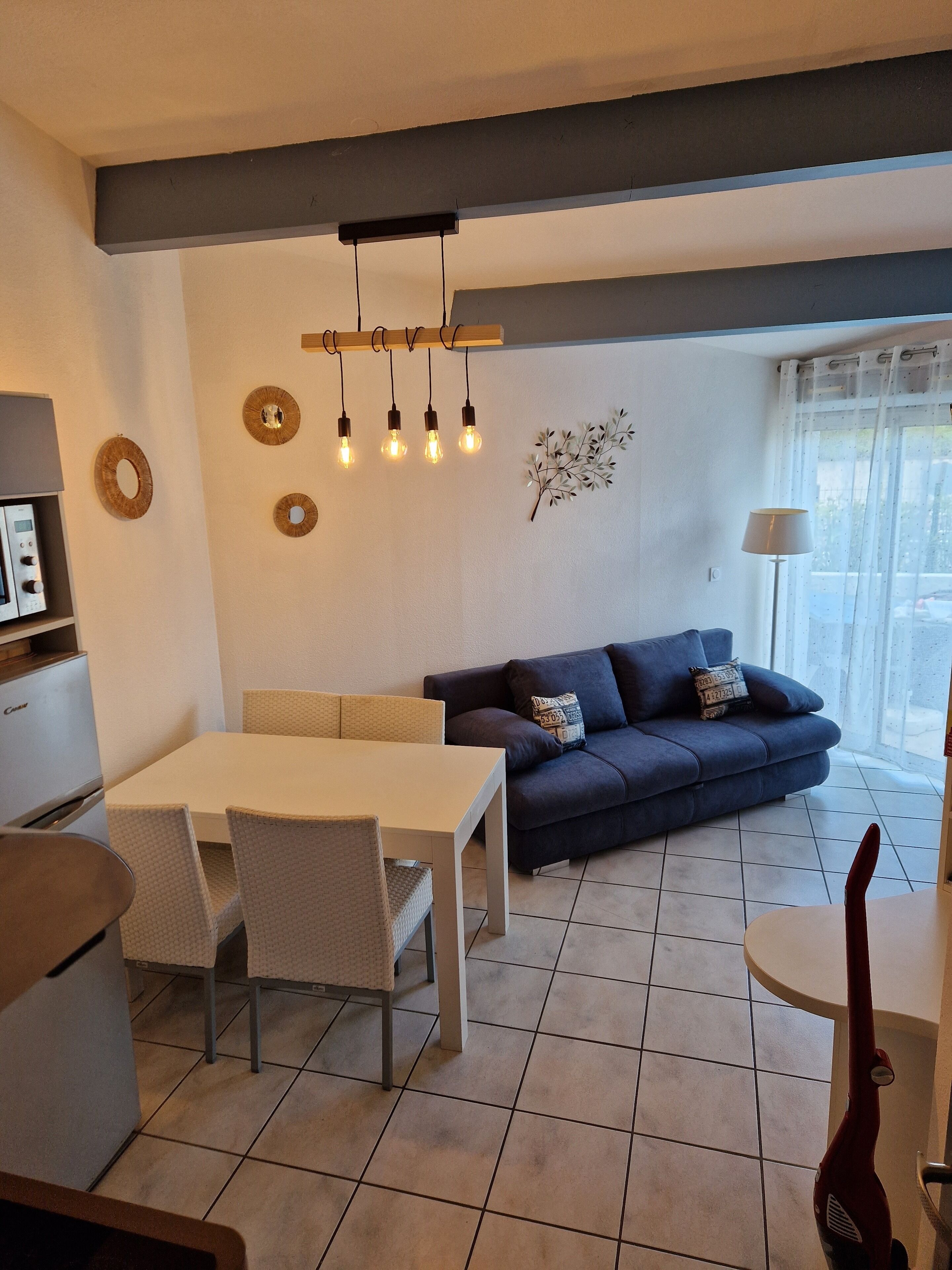 A modern living space with a dining area, a sofa, and a lamp.