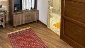 Een inloopkast met een ophangkast, een ingebouwde verwarming en een houten vloer.