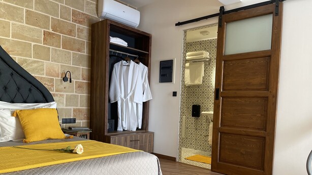 Een slaapkamer met een bed, een kledingkast, een dressoir en een badkamer met een schuifdeur.