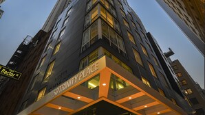 Een modern hotel met een opvallende ingang, waarop '50 Trinity Place' staat.